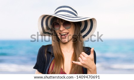 Young woman in bikini making phone gesture at the beach