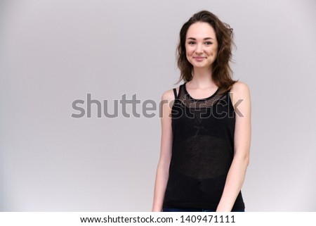 Life is a success. I am pleased with myself. Concept photo of a happy smiling woman satisfied life contented brunette girl in a black T-shirt on a gray background with flowing hair. Made in a studio.