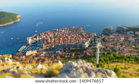 TILT SHIF EFFECT - Sightseeing of Dubrovnik at sunset. Adriatic sea and Dubrovnik Old Town panorama from the Kriz (Huge stone mountaintop cross) viewpoint in Dalmatia, Croatia.