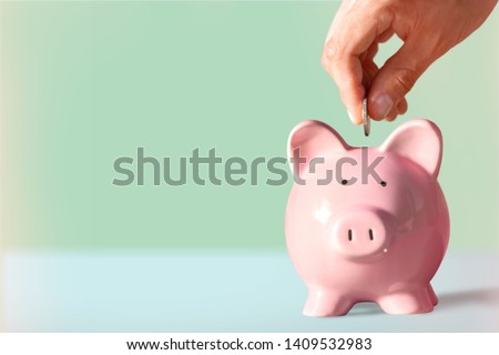 Hand putting coin to piggy bank Royalty-Free Stock Photo #1409532983