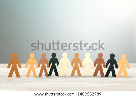 Row of paper people holding hands on table on light background