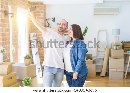 Young couple taking a picture photo using smartphone at new home, smiling happy for moving to new apartment