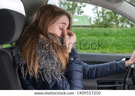 a woman driving overtired car and rubbing her eyes Royalty-Free Stock Photo #1409557250