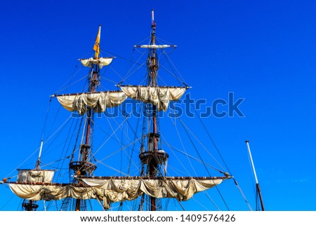 Sailing mast with sail under clear blue sky