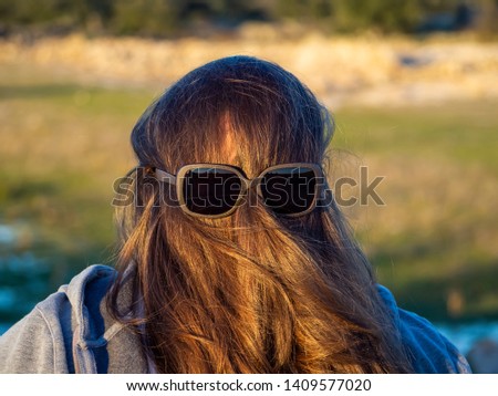 A curvy woman making funny gestures with hair in front of his face and sunglasses