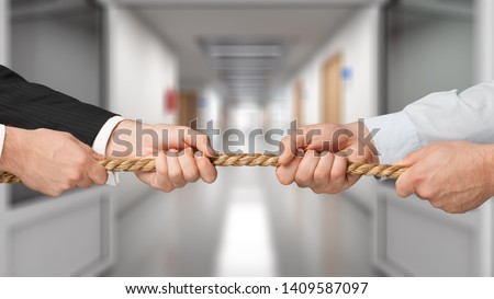 Business people pulling rope in opposite directions at office Royalty-Free Stock Photo #1409587097