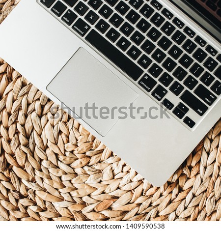 Laptop on straw background. Flat lay, top view minimal home office desk workspace.