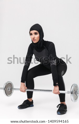 Image of young woman fitness muslim posing with barbell isolated over white wall background.