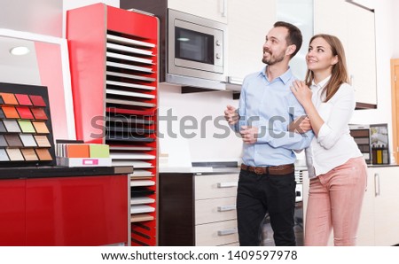 Smiling young family buying material for kitchen furniture in showroom