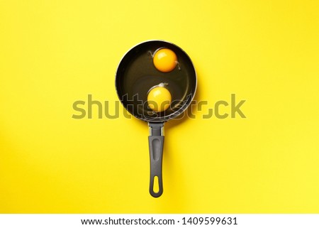 Food concept with two eggs, pan on yellow background. Top view. Creative pattern in minimal style. Flat lay