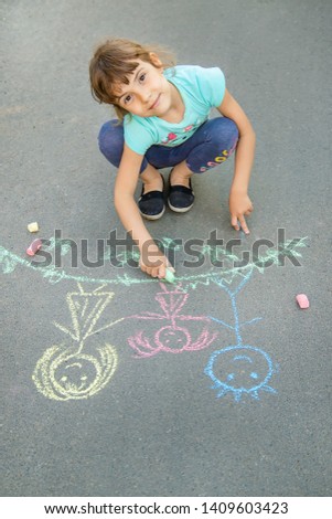 Child draws a family on the pavement with chalk. Selective focus. nature.