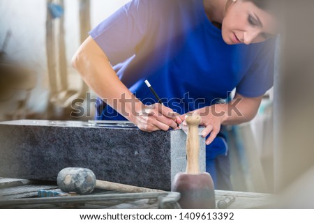 Diligent craftswoman applying template for engraving on headstone Royalty-Free Stock Photo #1409613392
