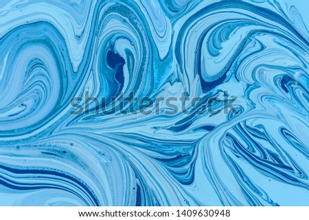 The mixing of the two liquid paints dark blue and light blue colors. Beautiful abstract two-color background. Coloring acrylic latex paint