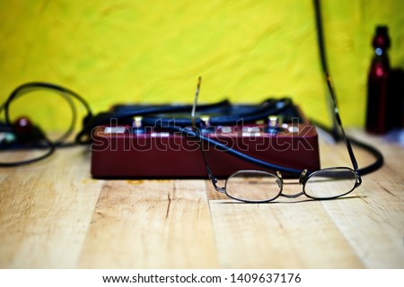Glasses leaning on a table leaning against a music changer.