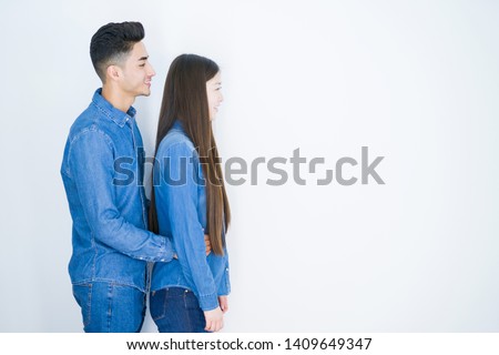 Beautiful young asian couple over white isolated background looking to side, relax profile pose with natural face with confident smile.