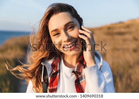Photo of happy young woman outside in free alternative vacation camping talking by mobile phone.