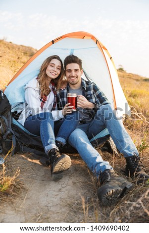 Photo of happy young loving couple outside in free alternative vacation camping drinking hot tea.