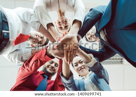 Team of diverse business people stacking their hands together, seen from below  Royalty-Free Stock Photo #1409699741