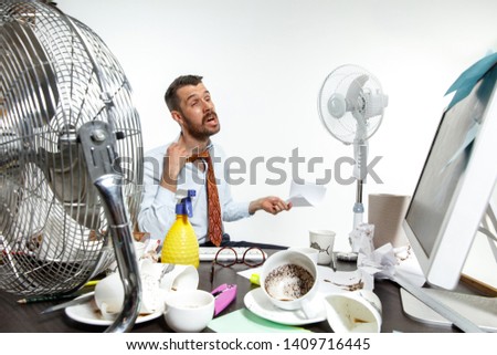 The true hell is here. Young man suffering from the heat in the office. Fans do not help, it's like sahara in the centre of the city. Concept of office worker's troubles, business, problems and stress