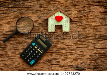 Home model with red heart and calculator and magnifier with searching put on the vintage wood background, Loan for real estate or saving money for buy a new house to family in the future concept.
