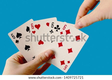 Top view of Playing cards in hands isolated on blue. background Showing Six from Each Suit - Hearts, Clubs, Spades and Diamonds. Space for text. Concept for games, gambling in casino.