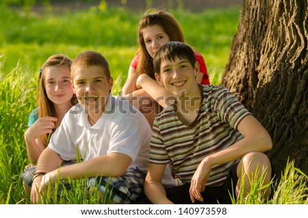 Four happy teenagers having fun in the nature on sunny spring day. Shallow depth of field. Focus is on the boy on the right.