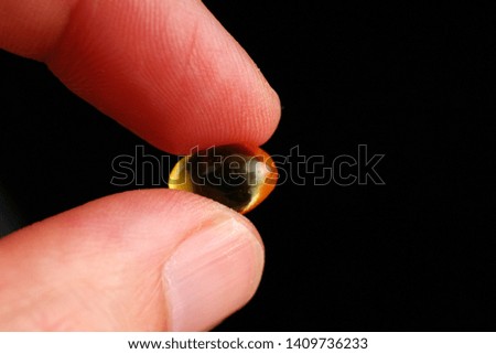 Fish oil in capsules in hand on a black background