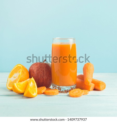 Fresh juice from carrots and orange apples in a glass on a wooden blue background. Selective focus. Copy space. Horizontal frame