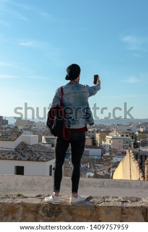 Young man with cap takes a picture with the city in the background. Lifestyle concept.