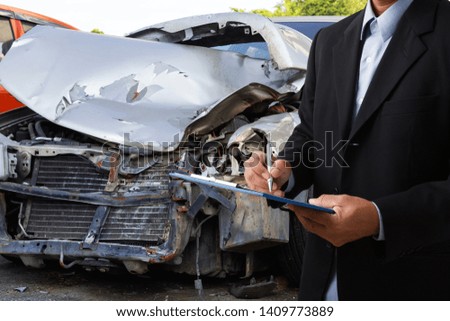Side view of insurance officer writing on clipboard while insurance agent examining black car after accident.
