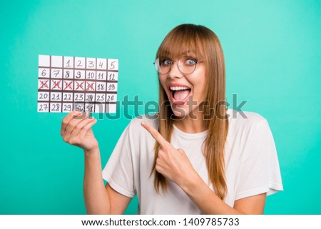 Close up photo amazing beautiful she her lady arms hands hold paper calendar days vacation weekend came direct index finger marked dates wear specs casual white t-shirt isolated teal green background