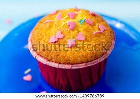 Delicious homemade colorful cupcakes with heart-shaped confectionery close up on a light blue wooden background