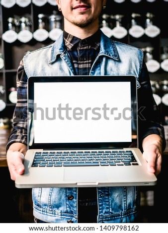 Guy holding Laptop with white screen in cafe mockup