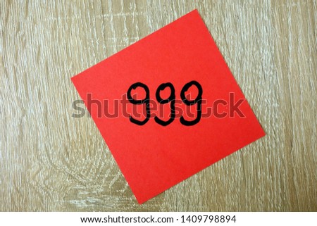 Emergency number 999 written on a red sticker, closeup
