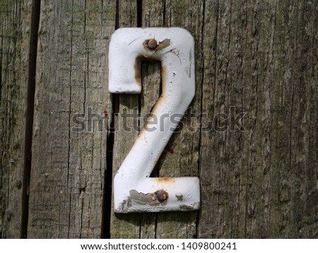 House number two. Old vintage number two door plate on old wooden fence