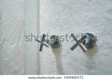 hot and cool silver tap for shower in bathroom on white cement wall