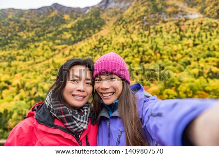 Mother daughter family self portrait selfie women taking picture with smartphone mobile app on outdoor forest hike in autumn nature landscape. Hikers lifestyle.