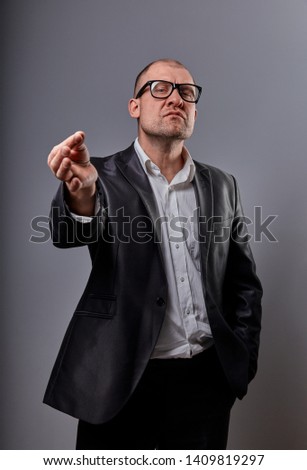 Fun comic bald business man in black fashion eyeglasses practicing the yoga and showing the zen sign on grey background. Closeup portait