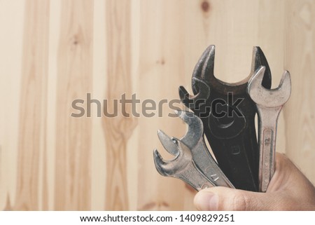 Spanners of different sizes in the male hand on a wooden background