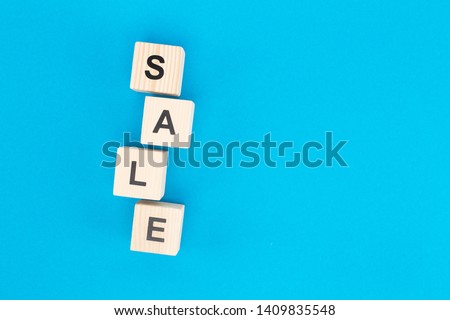 top view of sale lettering on wooden blocks on bright blue background with copy space