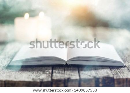 Islamic open book koran with the candle on grey wooden desk
