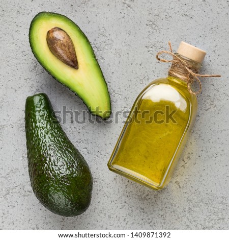Half and whole avocado and oil in bottle on concrete background top view. Super healthy food concept