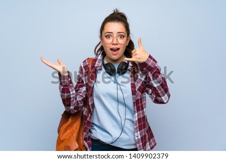 Teenager student girl over isolated blue wall making phone gesture and doubting
