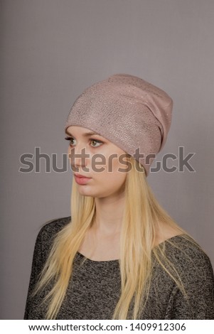 Portrait of a beautiful young girl in a stylish headdress with natural makeup on a gray background.