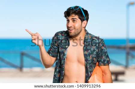 Man in trunks surprised and pointing finger to the side at the beach