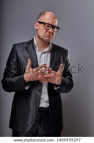Unhappy doubt busuness man in black suit and glasses showing the palm refusing sign on grey background. Closeup portrait