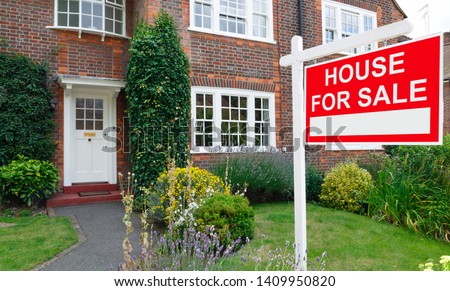 For sale sign outside a house in an affluent suburb of London