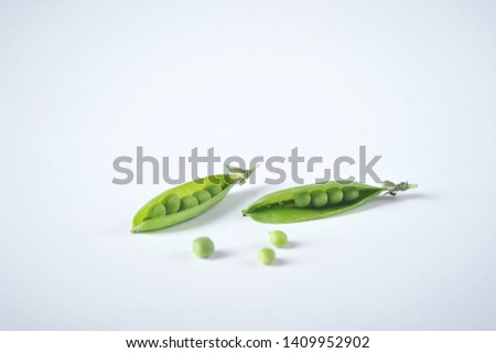 Two pods of fresh young green peas on a white background. Separate pea on the surface. Close-up.