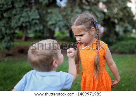 Two little children, sister and brother, quarreling and ready to beat each other crying during their walking, bad mood, negative emotion, upbringing and family concept, summer outdoor Royalty-Free Stock Photo #1409971985