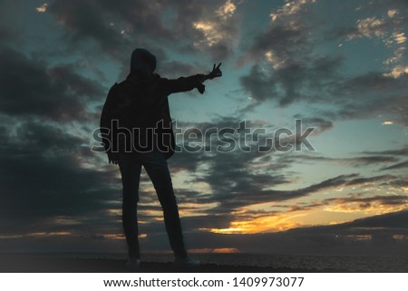 A silhouette of a man on the ocean shore at sunset